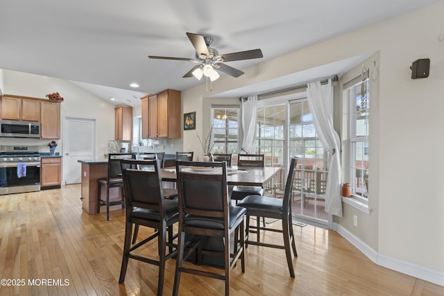 dining area featuring light wood finished floors, ceiling fan, baseboards, and vaulted ceiling