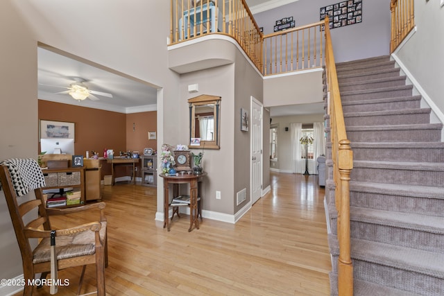 entryway with baseboards, visible vents, wood finished floors, stairs, and crown molding