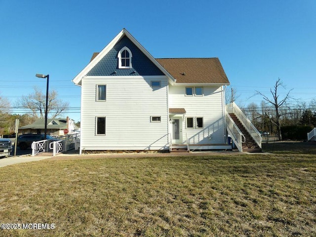 rear view of property featuring a lawn and stairs