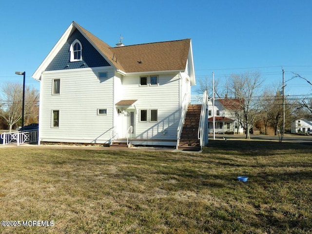 rear view of property with a yard and stairway