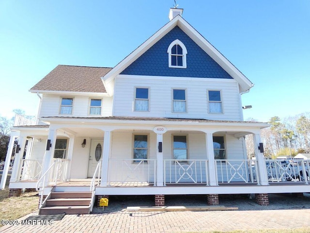 view of front of house with covered porch, roof with shingles, and a chimney