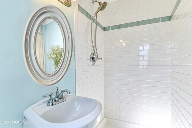 full bath featuring a tile shower and a sink