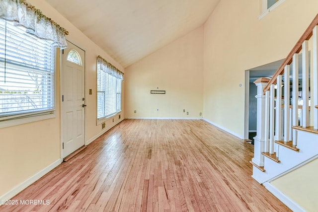 foyer entrance with high vaulted ceiling, wood finished floors, baseboards, and stairs