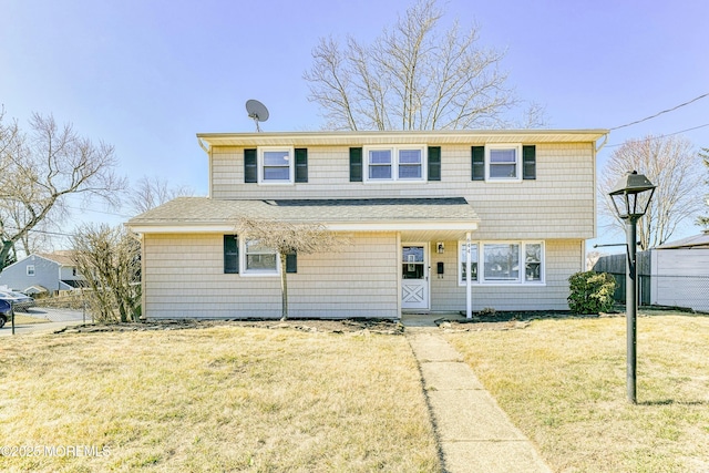 view of front of home with a front lawn, roof with shingles, and fence