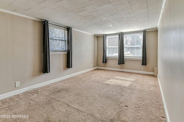 empty room with carpet, baseboards, and crown molding