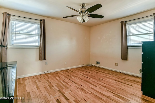 empty room with a ceiling fan, baseboards, plenty of natural light, and light wood finished floors