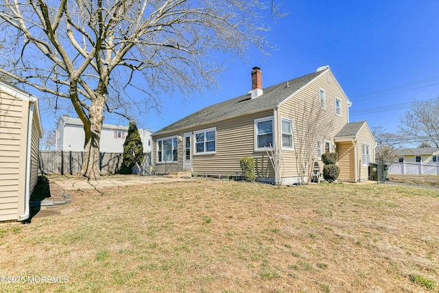 back of house featuring entry steps, a lawn, a chimney, and a fenced backyard