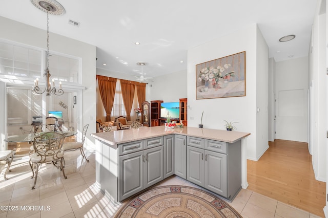 kitchen with gray cabinets, light countertops, a notable chandelier, and light tile patterned floors