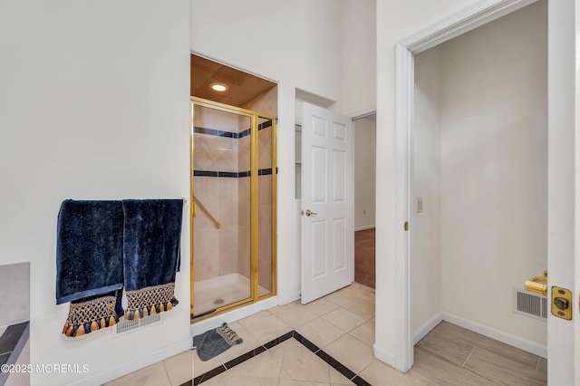 full bathroom with a stall shower, tile patterned flooring, visible vents, and baseboards