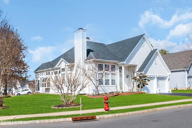 view of front of property featuring aphalt driveway, a garage, roof with shingles, a chimney, and a front yard