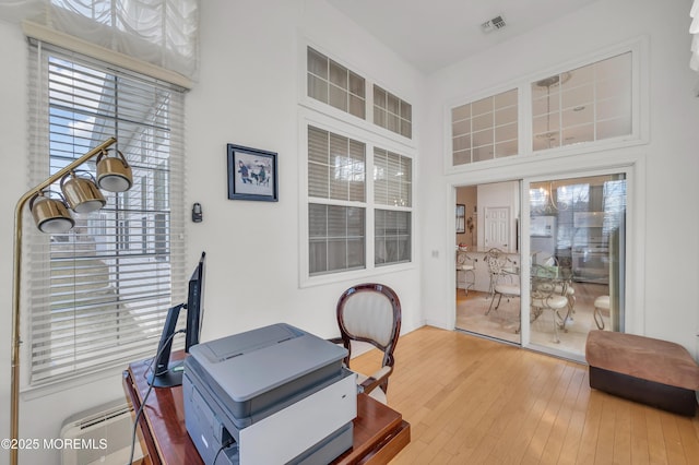 office featuring a high ceiling, visible vents, hardwood / wood-style floors, and a wall mounted AC