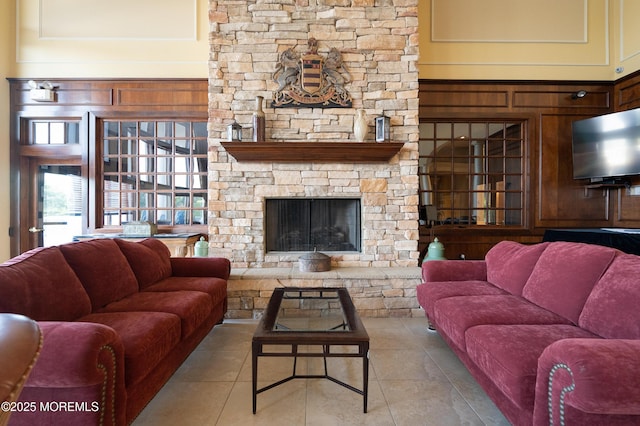 living room featuring tile patterned floors, a high ceiling, and a stone fireplace