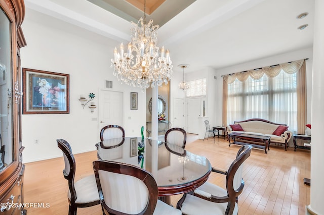 dining room featuring hardwood / wood-style floors, visible vents, and a notable chandelier