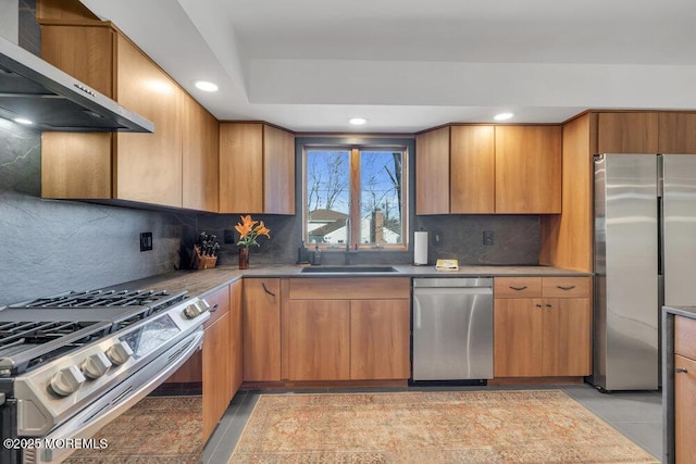 kitchen featuring decorative backsplash, recessed lighting, stainless steel appliances, wall chimney exhaust hood, and a sink