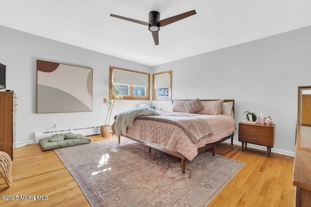 bedroom featuring baseboards, a baseboard heating unit, light wood-style floors, and a ceiling fan