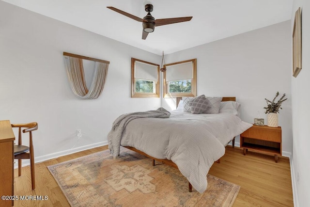 bedroom featuring baseboards, light wood-style flooring, and a ceiling fan