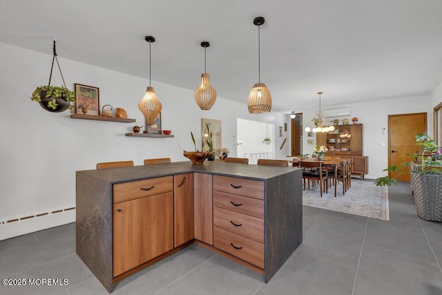 kitchen featuring tile patterned flooring, dark countertops, decorative light fixtures, and baseboard heating