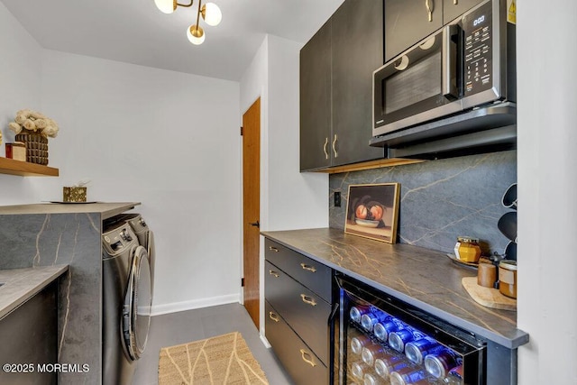 laundry room featuring baseboards, wine cooler, laundry area, washer and dryer, and a bar