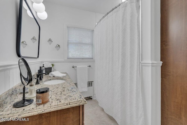 full bath featuring vanity, curtained shower, radiator heating unit, and wainscoting