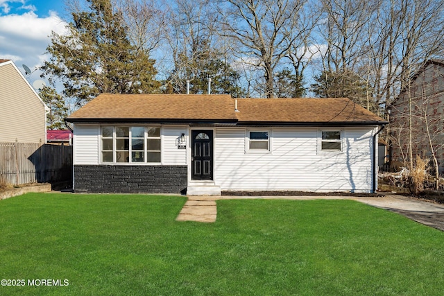 ranch-style house with stone siding, a front lawn, roof with shingles, and fence