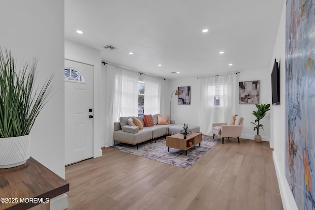 living room with light wood-type flooring, baseboards, visible vents, and recessed lighting