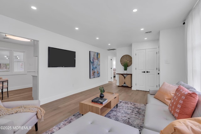 living area with recessed lighting, visible vents, baseboards, and wood finished floors