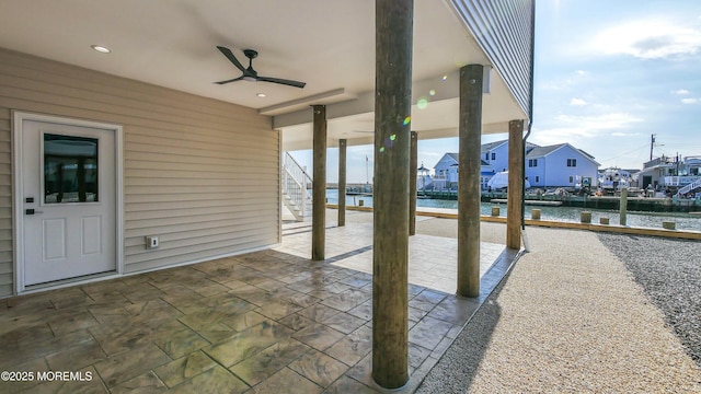 view of patio / terrace featuring a ceiling fan, a residential view, a water view, and stairs