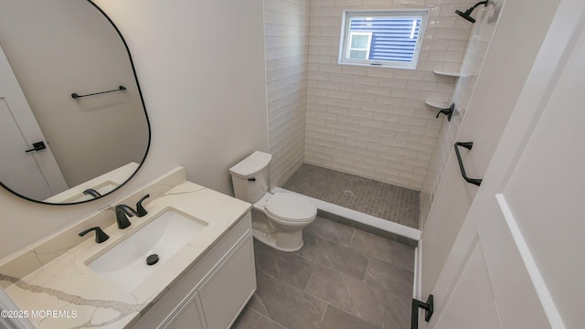 bathroom featuring tiled shower, vanity, and toilet