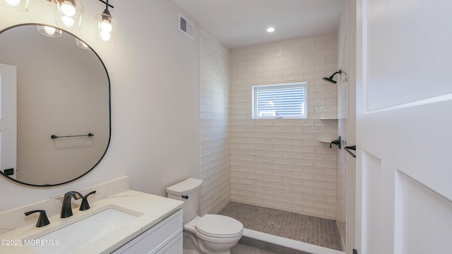 bathroom featuring toilet, recessed lighting, vanity, visible vents, and a tile shower