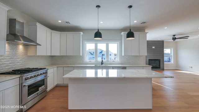 kitchen featuring stainless steel stove, visible vents, plenty of natural light, and wall chimney exhaust hood