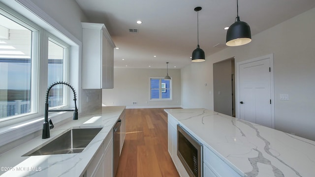 kitchen featuring light wood finished floors, recessed lighting, appliances with stainless steel finishes, white cabinetry, and a sink