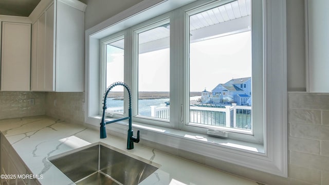 room details with white cabinetry, a sink, and light stone countertops