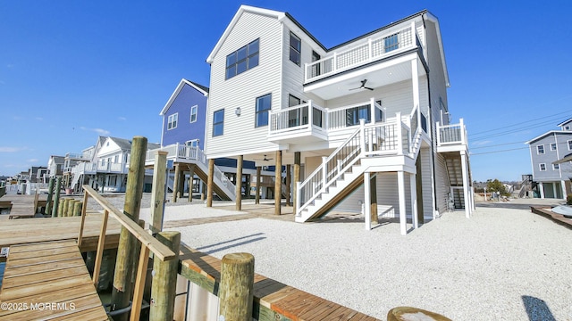 rear view of house with ceiling fan, stairway, a balcony, and a residential view