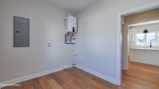 laundry room with water heater, wood finished floors, electric panel, and baseboards