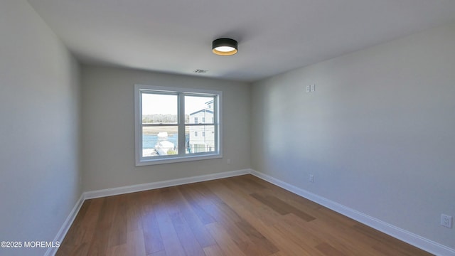 spare room featuring baseboards, visible vents, and dark wood-style flooring