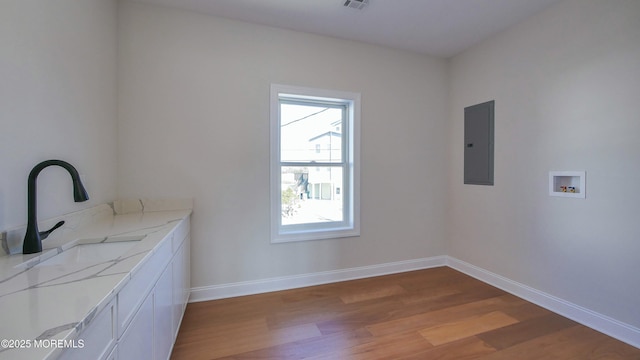 laundry room with cabinet space, electric panel, baseboards, wood finished floors, and washer hookup