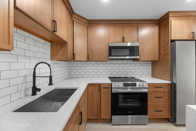 kitchen with brown cabinets, a sink, backsplash, stainless steel appliances, and light countertops