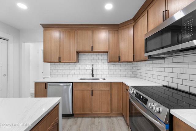 kitchen featuring decorative backsplash, stainless steel appliances, light countertops, and a sink