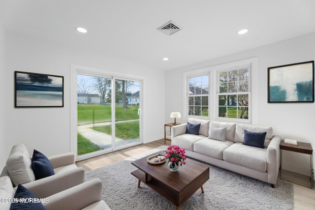 living room with light wood-type flooring, visible vents, baseboards, and recessed lighting