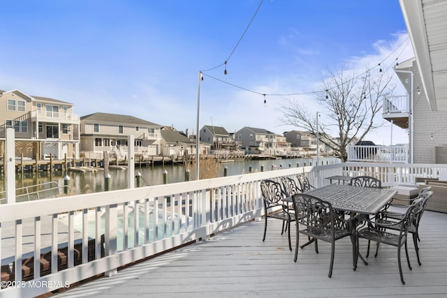 wooden terrace featuring a water view, a residential view, and outdoor dining space