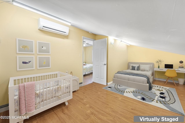 bedroom featuring wood finished floors, vaulted ceiling, and a wall mounted AC