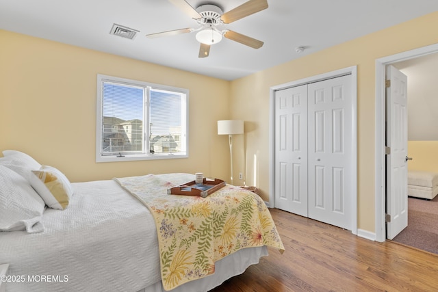 bedroom featuring baseboards, visible vents, a ceiling fan, wood finished floors, and a closet