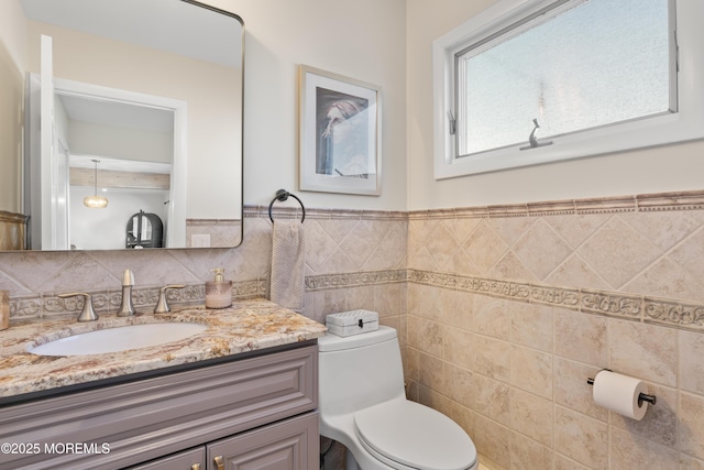 bathroom featuring toilet, wainscoting, tile walls, and vanity