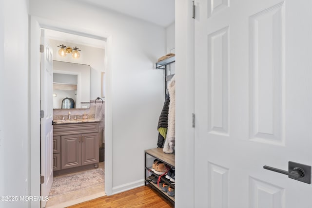 mudroom with light wood-type flooring, baseboards, and a sink