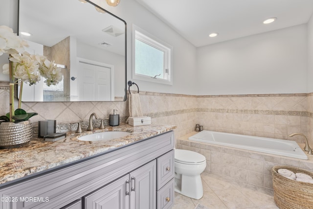 full bath featuring toilet, a bath, tile patterned flooring, vanity, and tile walls