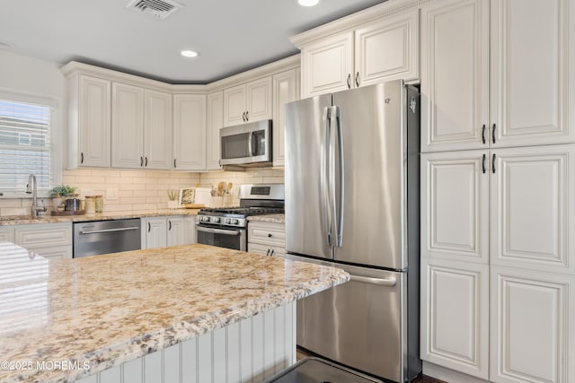 kitchen featuring visible vents, appliances with stainless steel finishes, decorative backsplash, and a sink