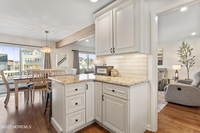 kitchen with tasteful backsplash, dark wood-style flooring, beam ceiling, and light stone countertops