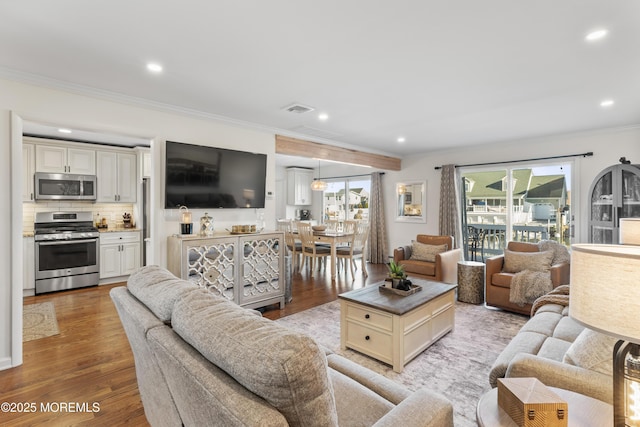 living area with light wood-style floors, recessed lighting, visible vents, and crown molding