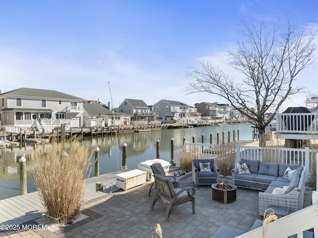 view of patio / terrace featuring a residential view, an outdoor living space with a fire pit, a water view, and a boat dock