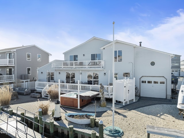 rear view of house featuring a garage, a hot tub, a balcony, and a deck